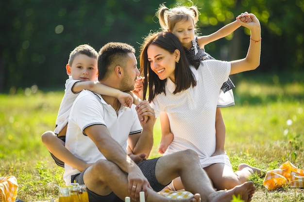 Família alegre fazendo piquenique. Pais jantando com os filhos ao ar livre.