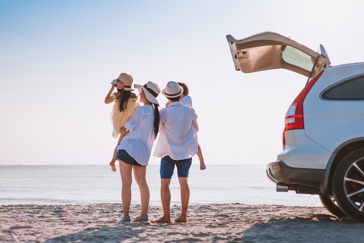 Foto familia alegre de pie en la playa contra el cielo