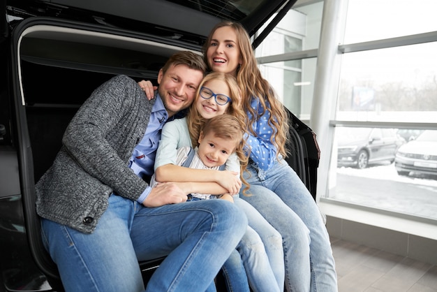 Familia alegre posando en el baúl del automóvil.