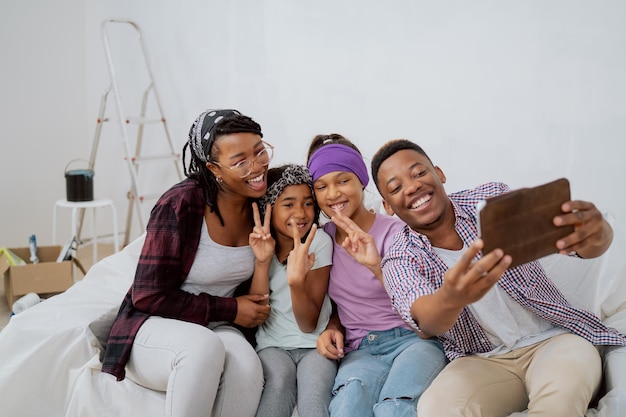 Família alegre renova um novo apartamento pai rindo tira uma selfie com sua esposa e filhos