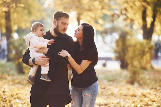 Família alegre se divertindo junto com seu filho no belo parque de outono.