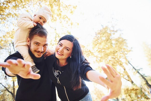 Foto família alegre se divertindo junto com seu filho no belo parque de outono.