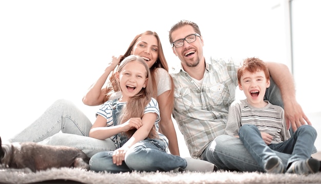 Familia alegre sentada en la alfombra en la nueva sala de estar el concepto de felicidad