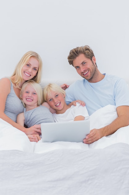 Família alegre, usando um laptop na cama
