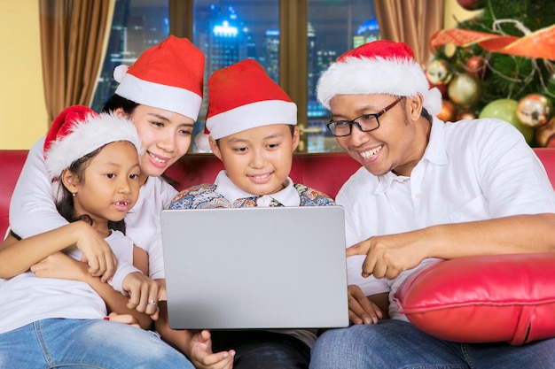 Família alegre usando um laptop na época do Natal