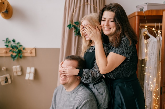 Familia amable con caras sonrientes que cierran los ojos en una habitación acogedora y decorada