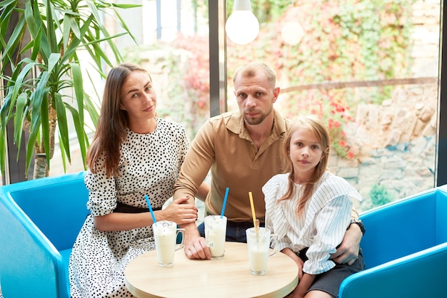 Família amigável tomando milkshakes no café