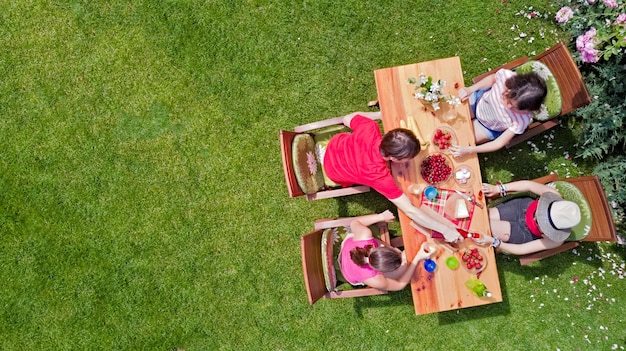 Familia y amigos comiendo juntos al aire libre en una fiesta en el jardín de verano Vista aérea de la mesa con comida