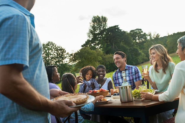 Una familia y amigos sentados en una mesa al aire libre comiendo