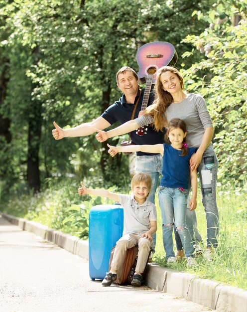 Familia amistosa alegre con maletas deja de pasar coche