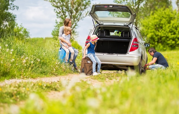 Familia amistosa cambia el neumático del coche.