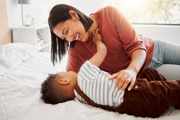 Família amorosa feliz com mãe e filho sendo brincalhão e se unindo em uma cama em casa Pai sorridente brincando com seu filho rindo e curtindo a maternidade Pai solteiro abraçando seu filho