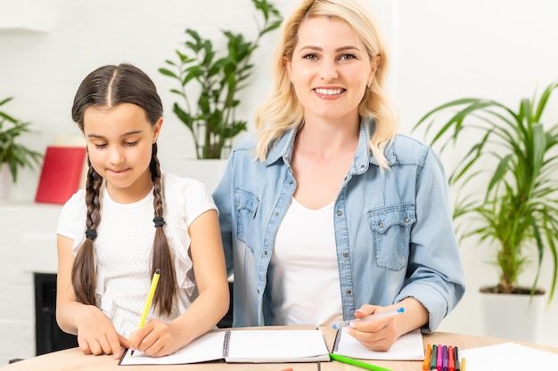 Família amorosa feliz. mãe e sua filha criança brincando e fazendo lição de casa.