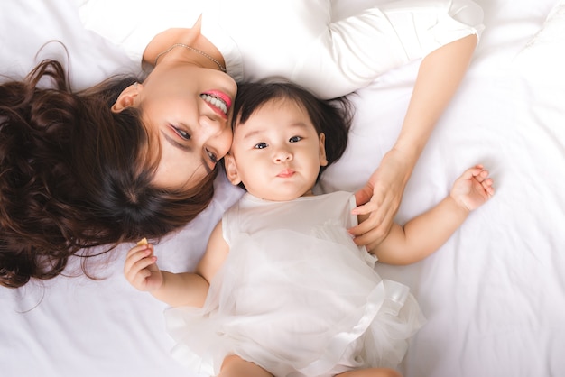 Família amorosa feliz. Menina mãe e criança estão se divertindo na cama.