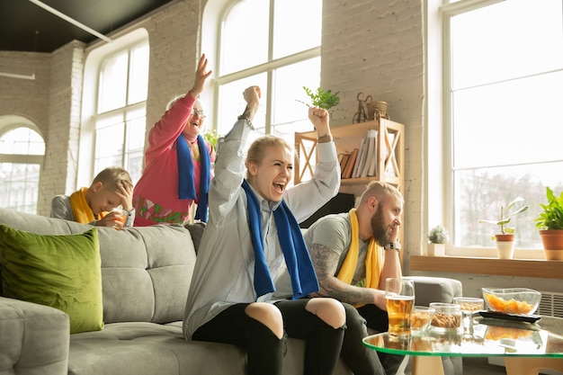 Família animada assistindo futebol, jogo de esporte em casa. Avós, pais e filhos torcendo pelo basquete, futebol, tênis, futebol, time de hóquei nacional favorito. Conceito de emoções, suporte.