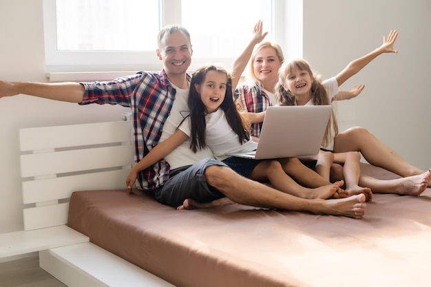 Foto familia animada comprando en línea acostado en la cama en casa