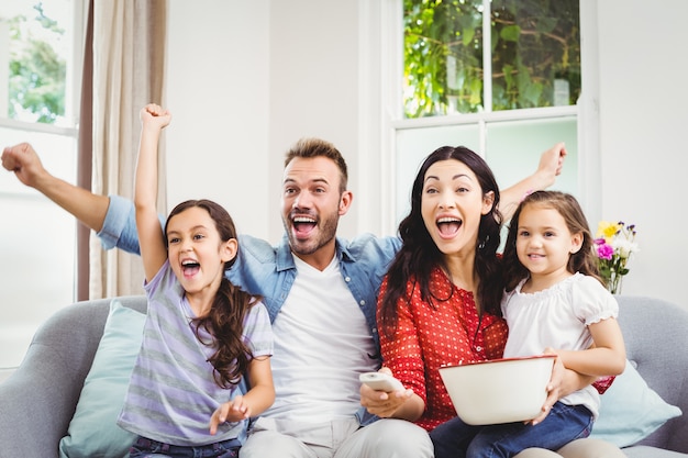 Familia animando mientras mira televisión en casa