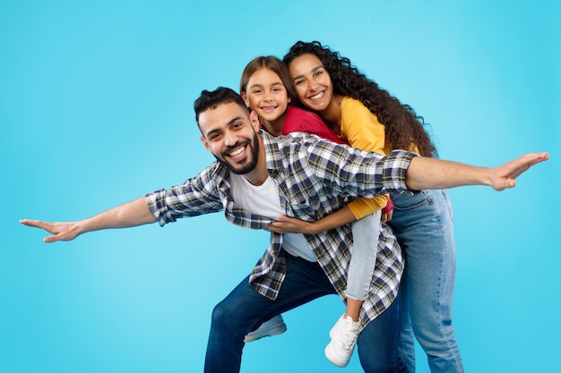 Familia árabe divirtiéndose posando juntos sobre fondo azul.