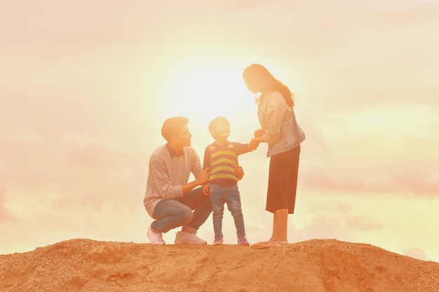 Foto familia en la arena contra el cielo durante la puesta de sol