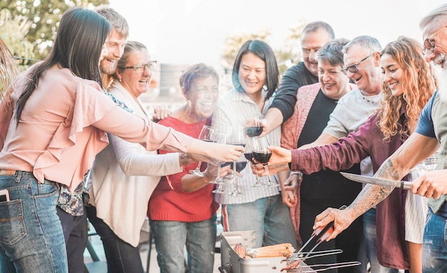 Familia asar carne y animar con vino tinto en una barbacoa al aire libre