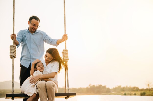 Familia asiática balanceándose en un columpio en un entorno de naturaleza serena