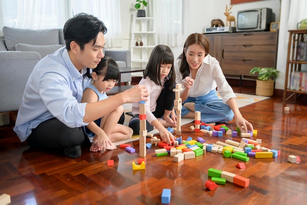 Família asiática com crianças brincando e construindo torre de blocos de brinquedos de madeira coloridos