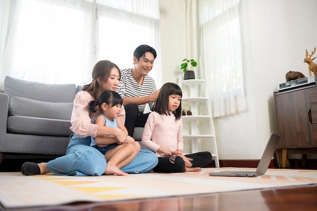Família asiática com crianças usando laptop em casa