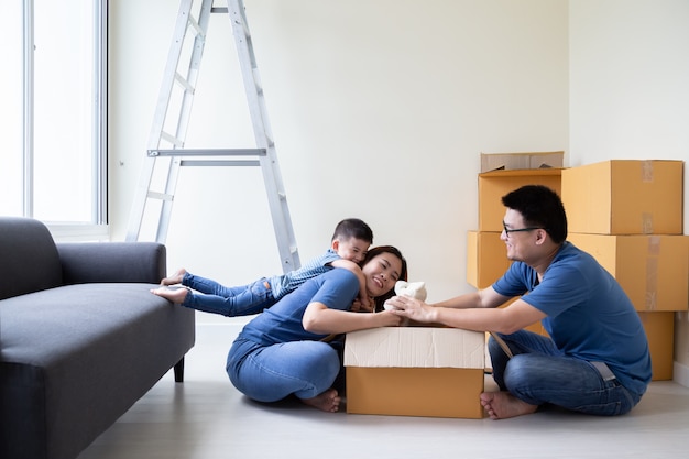 Família asiática, desembalar caixas de papelão na nova casa, mudar para novo conceito de propriedade imobiliária