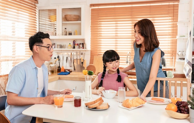 La familia asiática disfruta desayunando juntos en la cocina de su casaxA