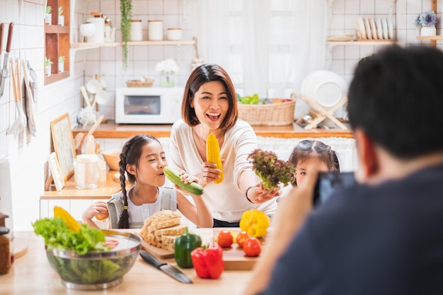 La familia asiática disfruta jugando y cocinando comida en la cocina de casa