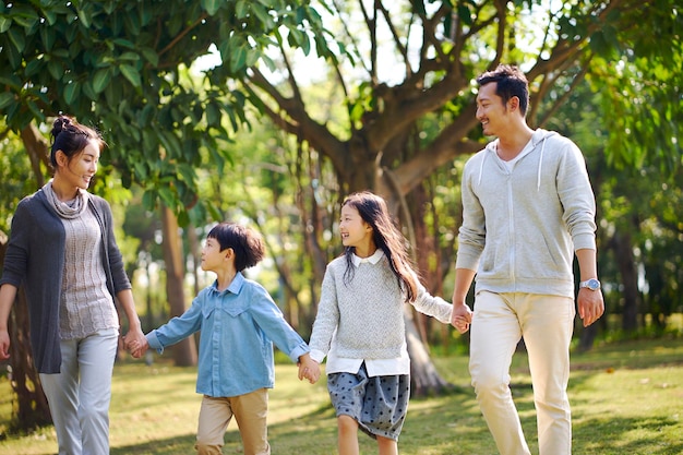 familia asiática con dos hijos caminando relajándose divirtiéndose en el parque