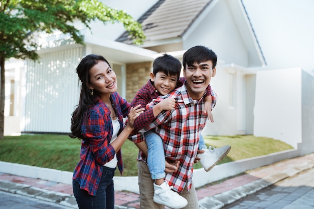 Família asiática em pé na frente de sua nova casa juntos