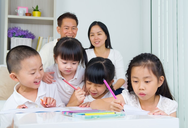 Família asiática fazendo lição de casa da escola na sala de estar