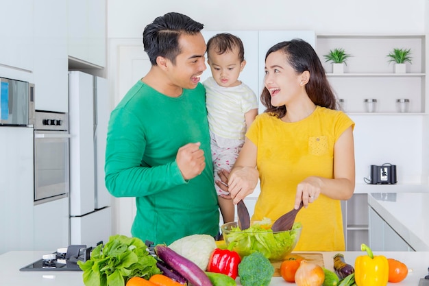 Família asiática fazendo salada de vegetais na cozinha