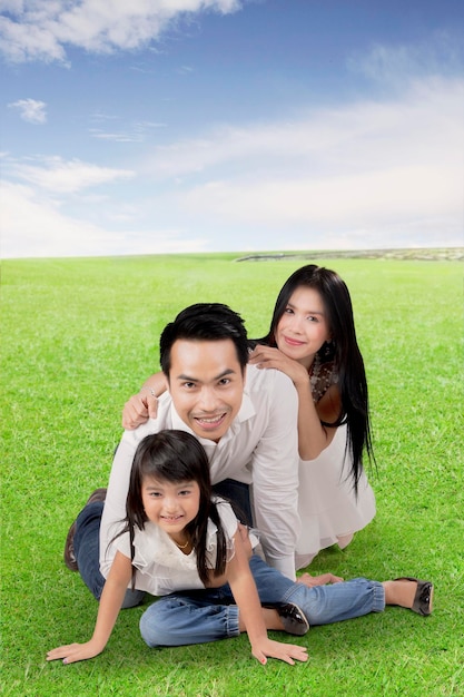 Família asiática feliz aproveitando o verão posando juntos em um prado