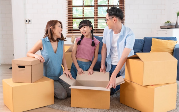 Familia asiática feliz con caja de cartón en casa nueva. Concepto de reubicación