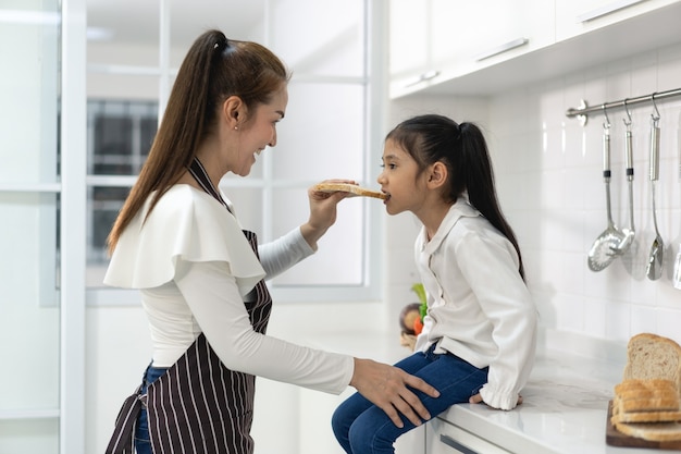 Família asiática feliz com a filha fazendo massa e preparando biscoitos, filha ajuda os pais a preparar o bolo conceito de família