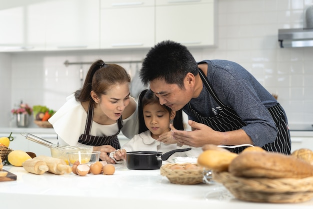 família asiática feliz com filha fazendo massa e preparando biscoitos