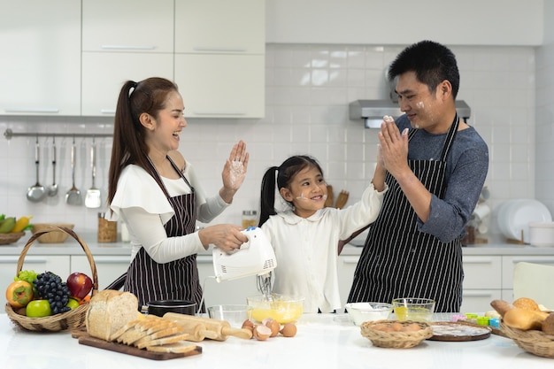 família asiática feliz com filha fazendo massa e preparando biscoitos