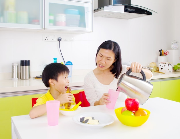 Familia asiática feliz desayunando en la cocina