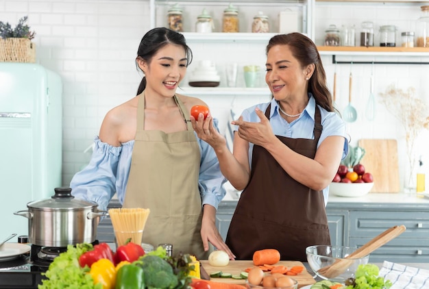 Familia asiática feliz haciendo ensalada en la cocina en casa Disfrute de la actividad familiar juntos