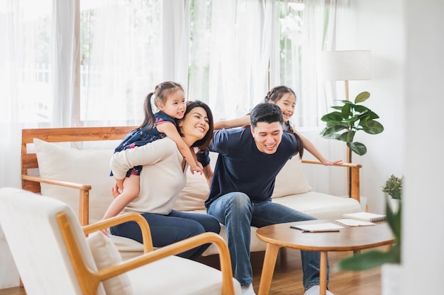 Foto familia asiática feliz jugando juntos en la sala de estar de la casa del sofá