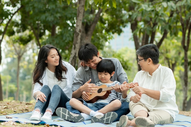 Família asiática feliz passando tempo juntos ao ar livre na natureza verde e no parque férias do conceito dos pais