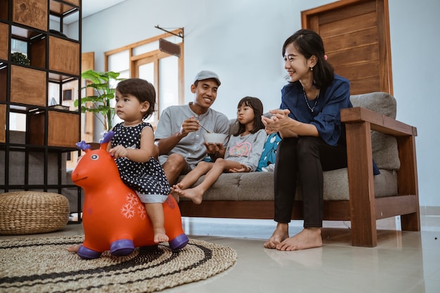 Família asiática feliz sentada no sofá em casa assistindo tv juntos