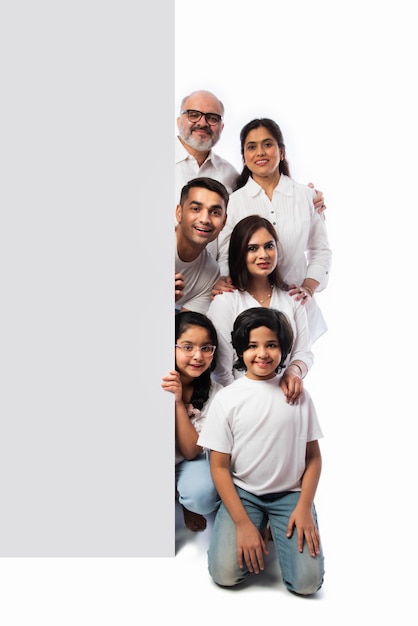 Familia asiática india multigeneracional con pizarra blanca, señalando o presentando letrero blanco vacío