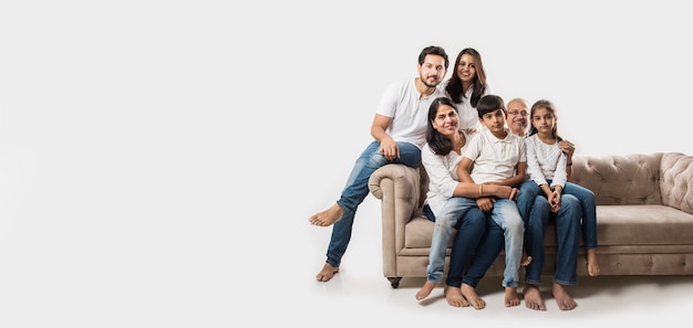 Familia asiática india sentada en un sofá o un sofá sobre fondo blanco.