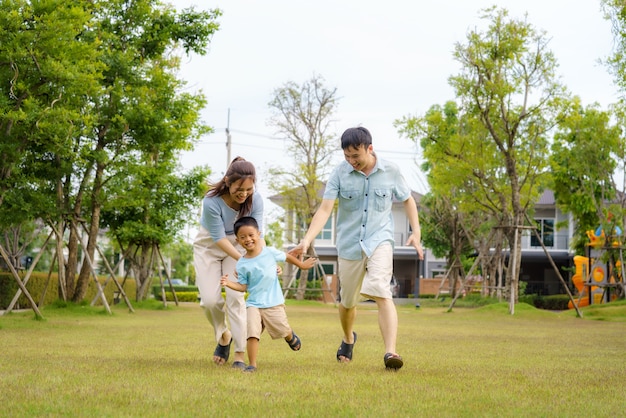 Família asiática jogando bola no quintal ou parque público na vizinhança para a saúde e o bem-estar diário, família feliz física e mental.