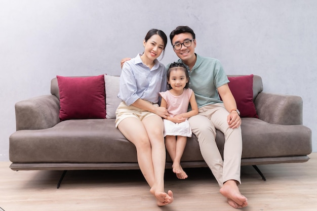 Familia asiática joven que se sienta en el sofá