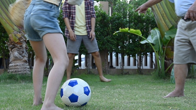 Foto la familia asiática juega al fútbol en el jardín de casa. los padres con niños y abuelos juegan al fútbol en el patio trasero.
