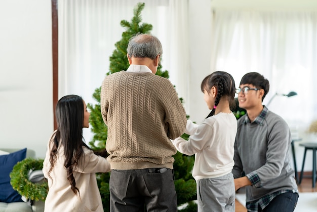 Família asiática multigeracional decorando uma árvore de natal